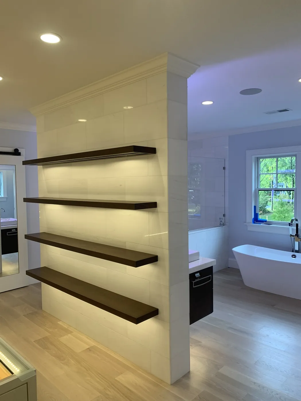 Floating shelf partition dividing the vanity from the tub area
