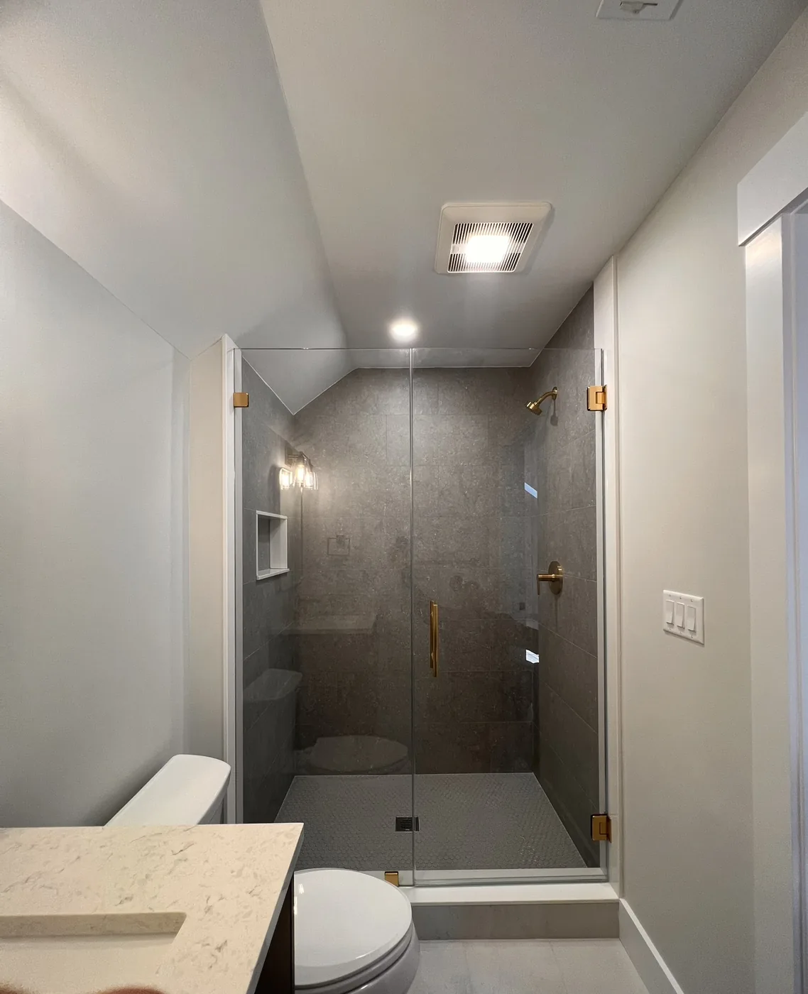 Gray tile shower with a frameless glass door