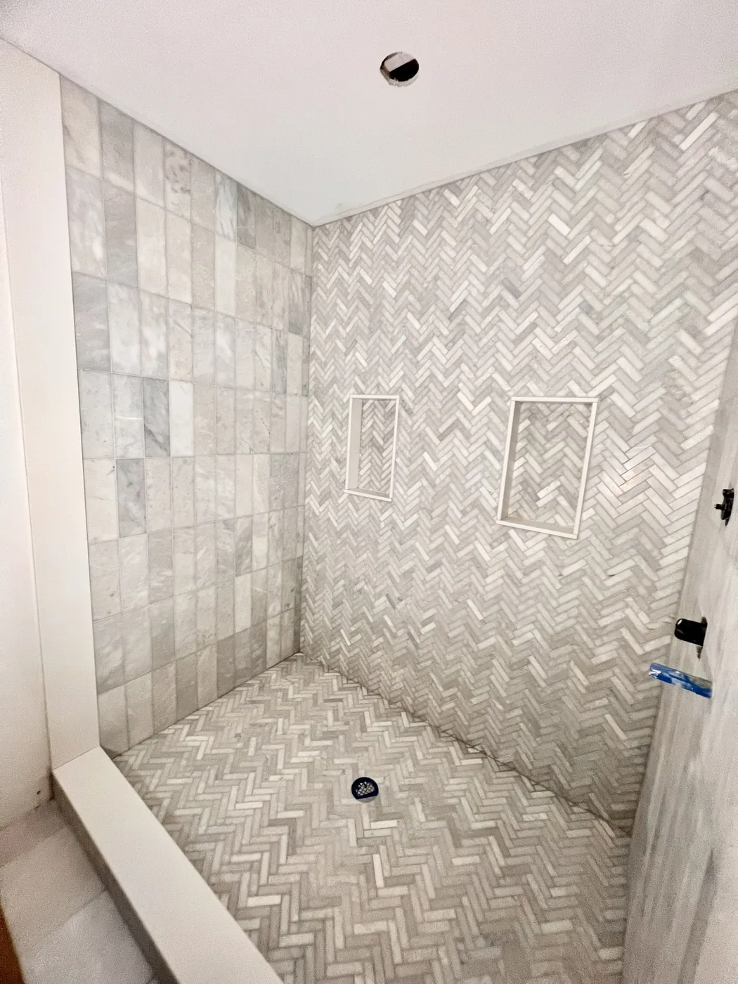 Herringbone marble tile shower with two recessed niches