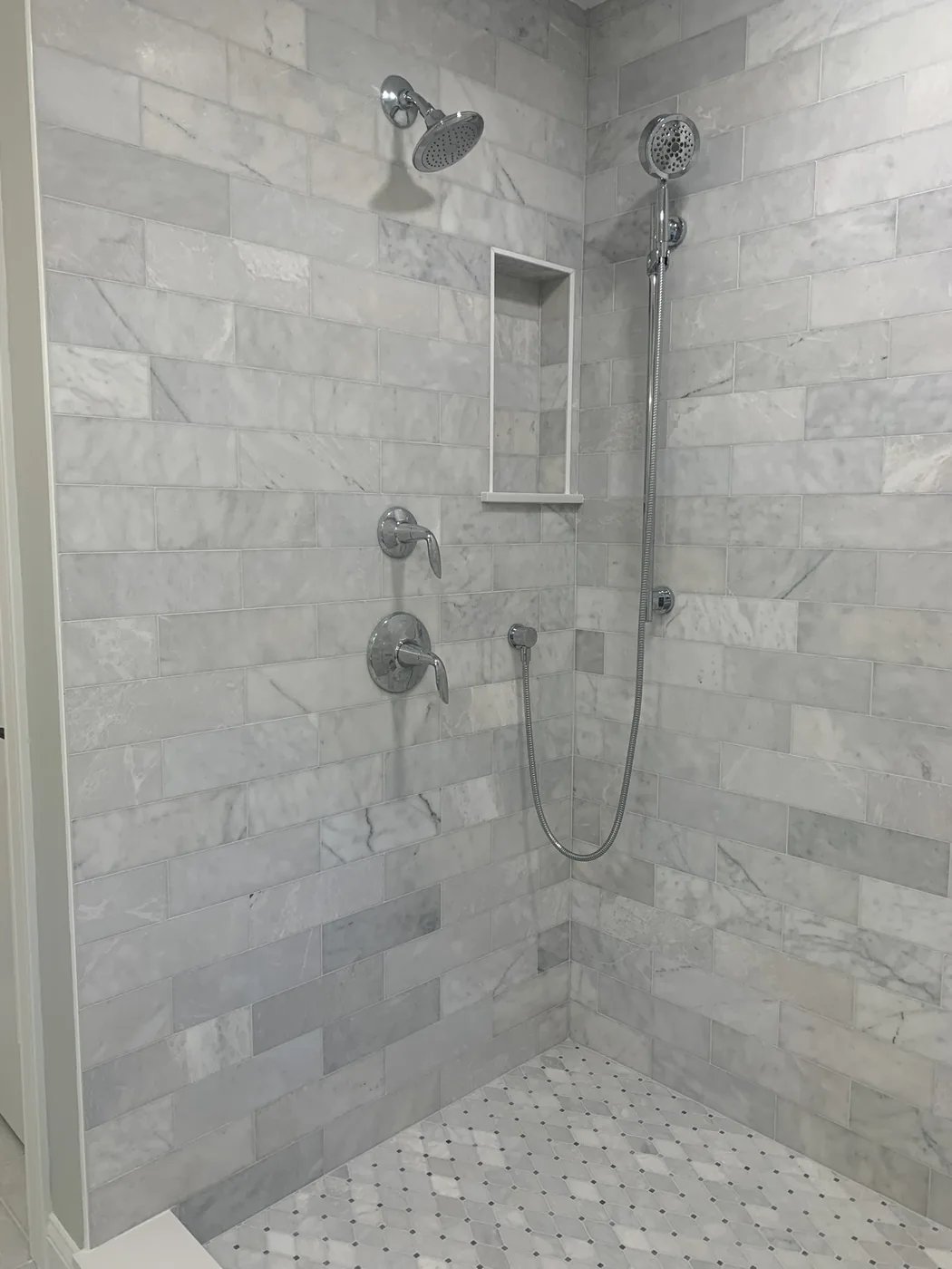 Shower finished in marble subway tile with a recessed niche