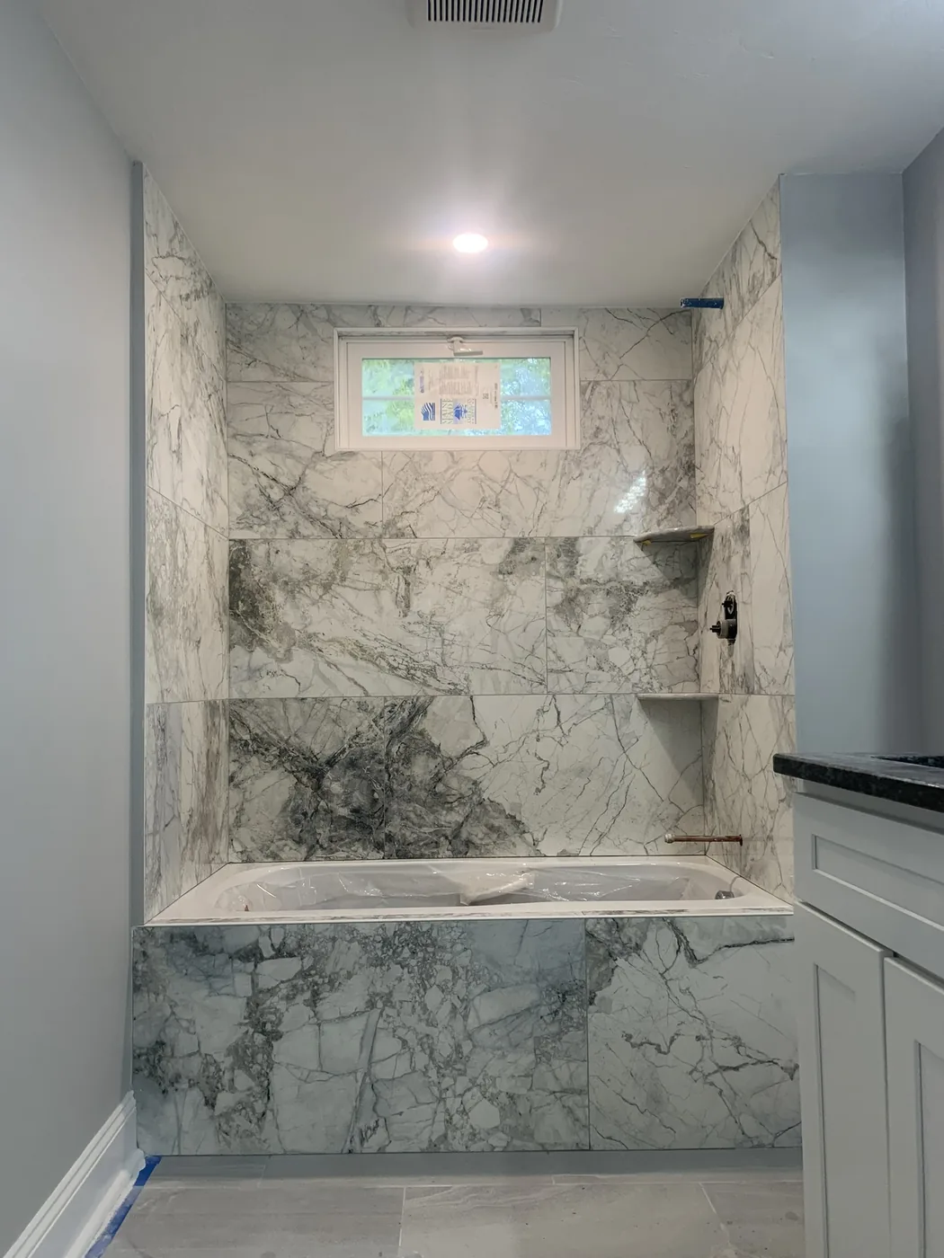 Marble slab tub surround with a window above