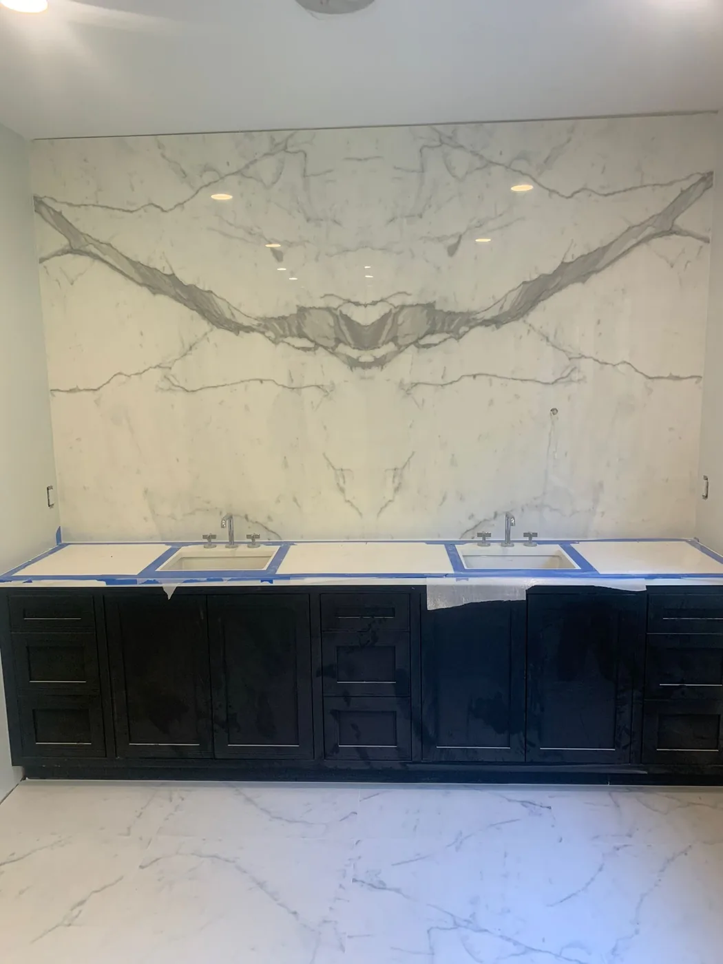 Bookmatched marble slab wall behind a double vanity