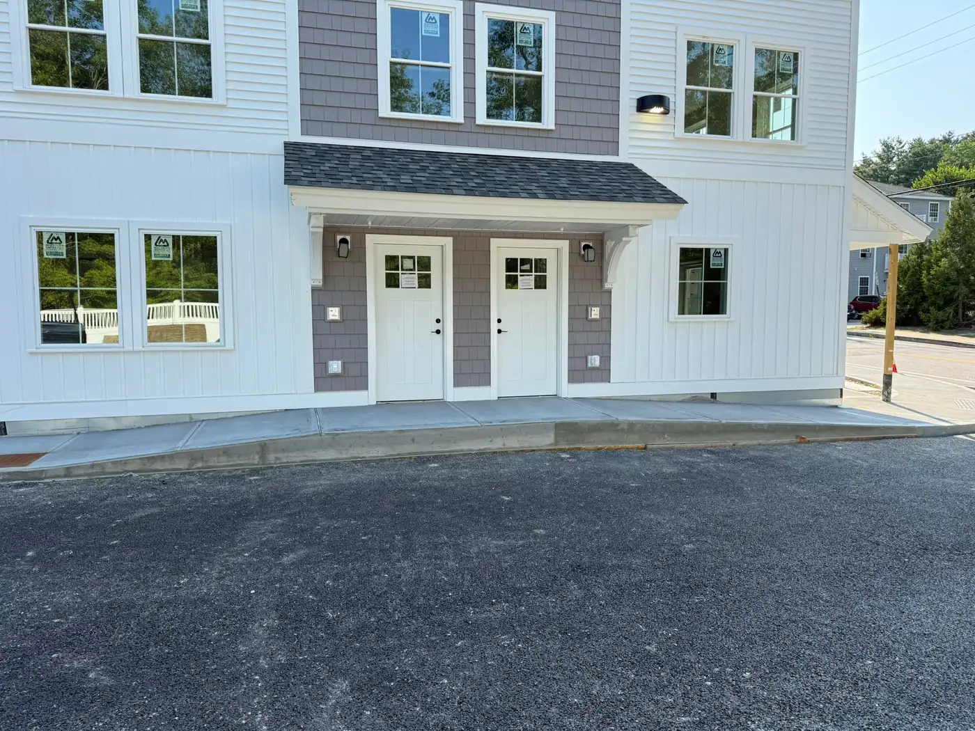 Two entry doors under a shed roof on a white sided duplex