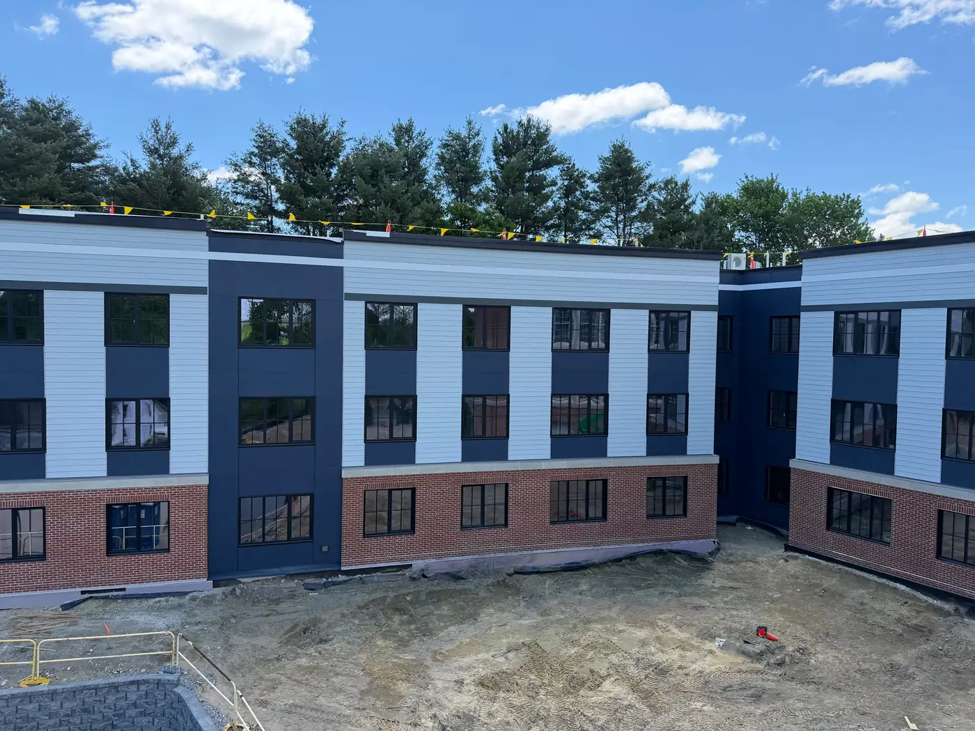Multifamily building with sage lap siding, navy panels and a brick base