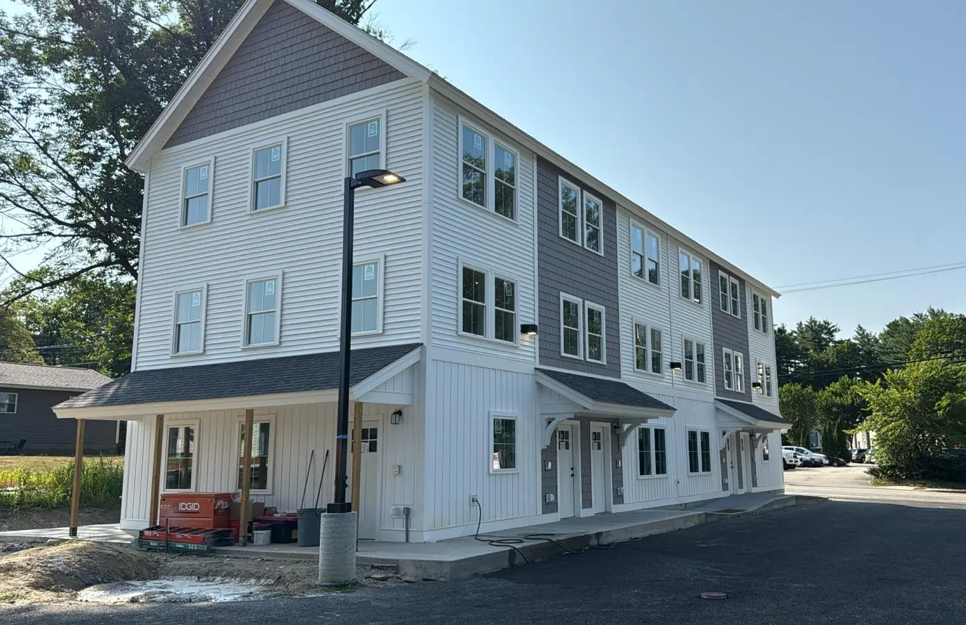 Three story townhomes with white and gray siding and covered entries