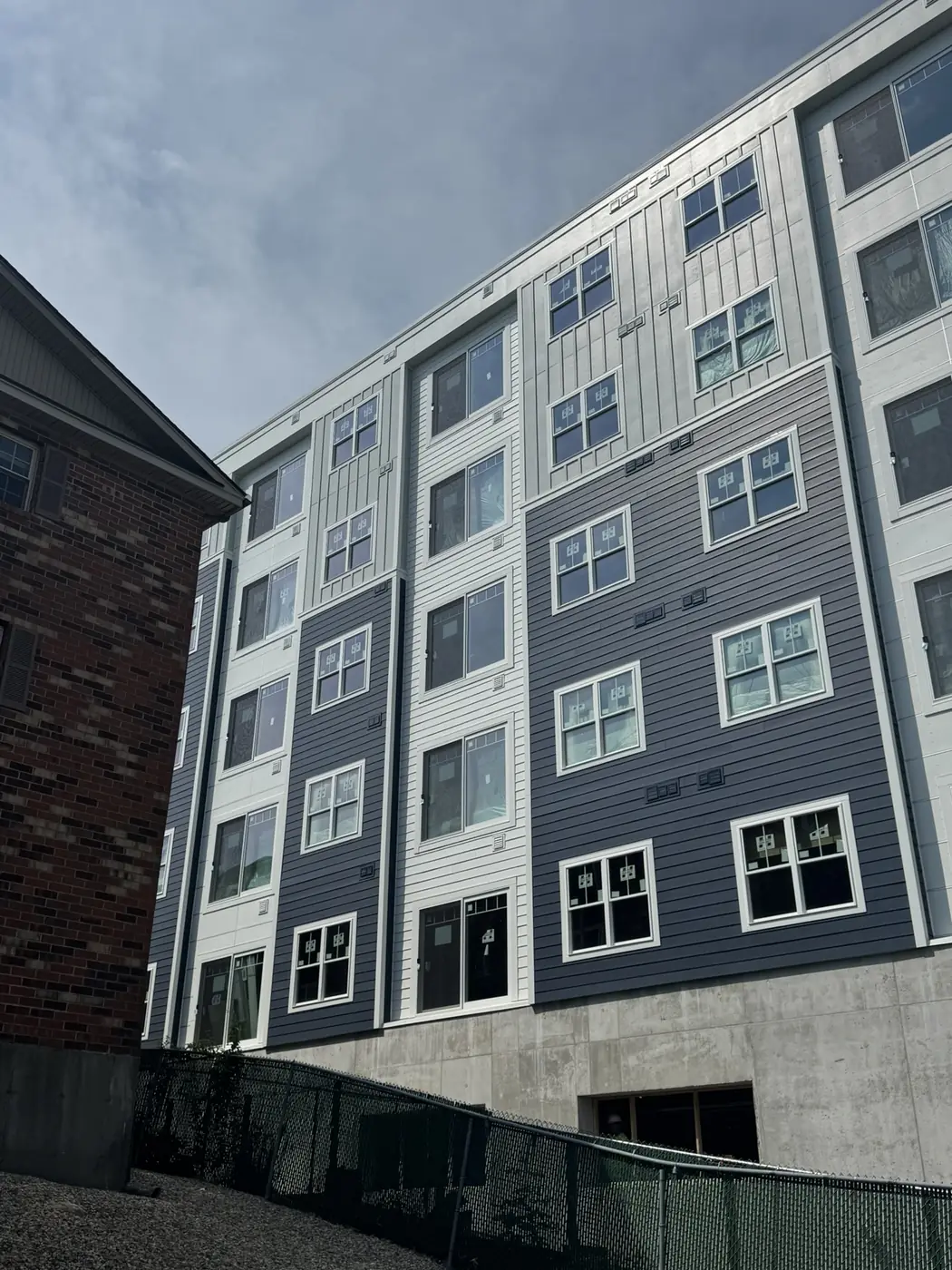Apartment building in navy and white siding above a concrete base, seen from below
