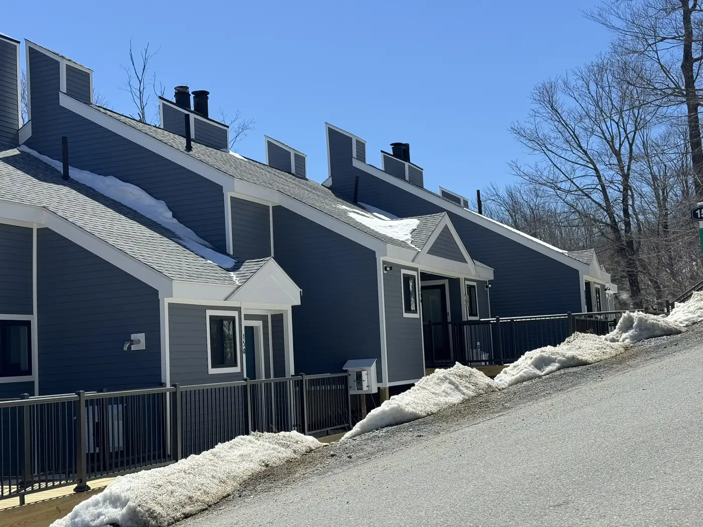 Row of townhouse units in dark blue lap siding with white trim, with snow on the ground
